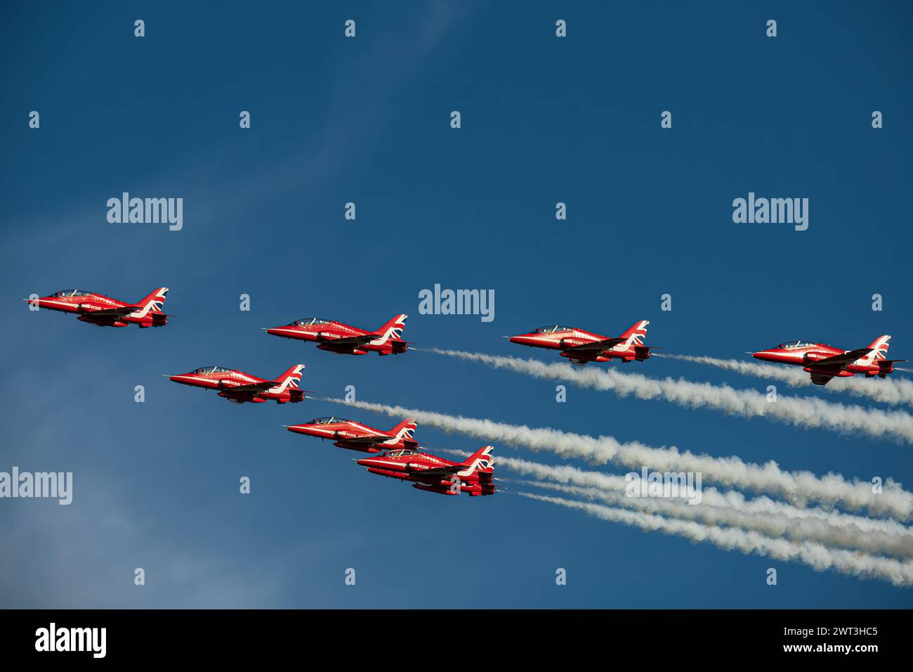 Squadrone di frecce rosse in volo contro il cielo blu e lasciando sentieri di fumo bianchi Foto Stock