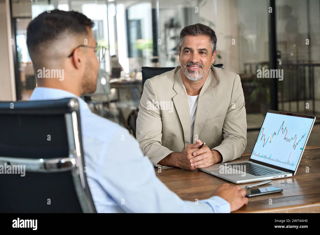 L'investitore del mercato azionario e il consulente finanziario discutono i dati di negoziazione utilizzando un laptop. Foto Stock