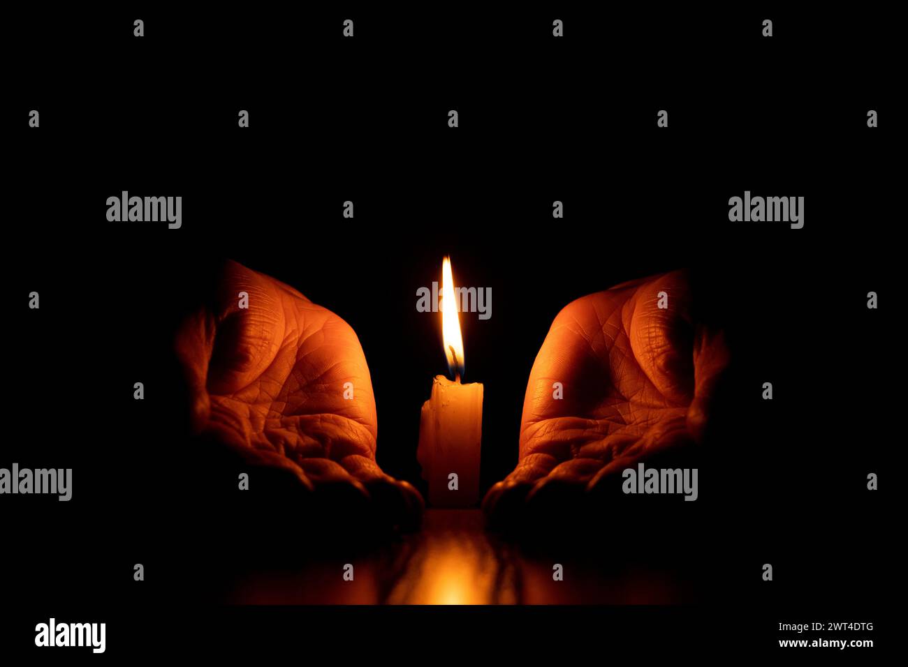 Le mani delle donne vicino a una fiamma di candela nel buio, la fede e la religione, pregando Foto Stock