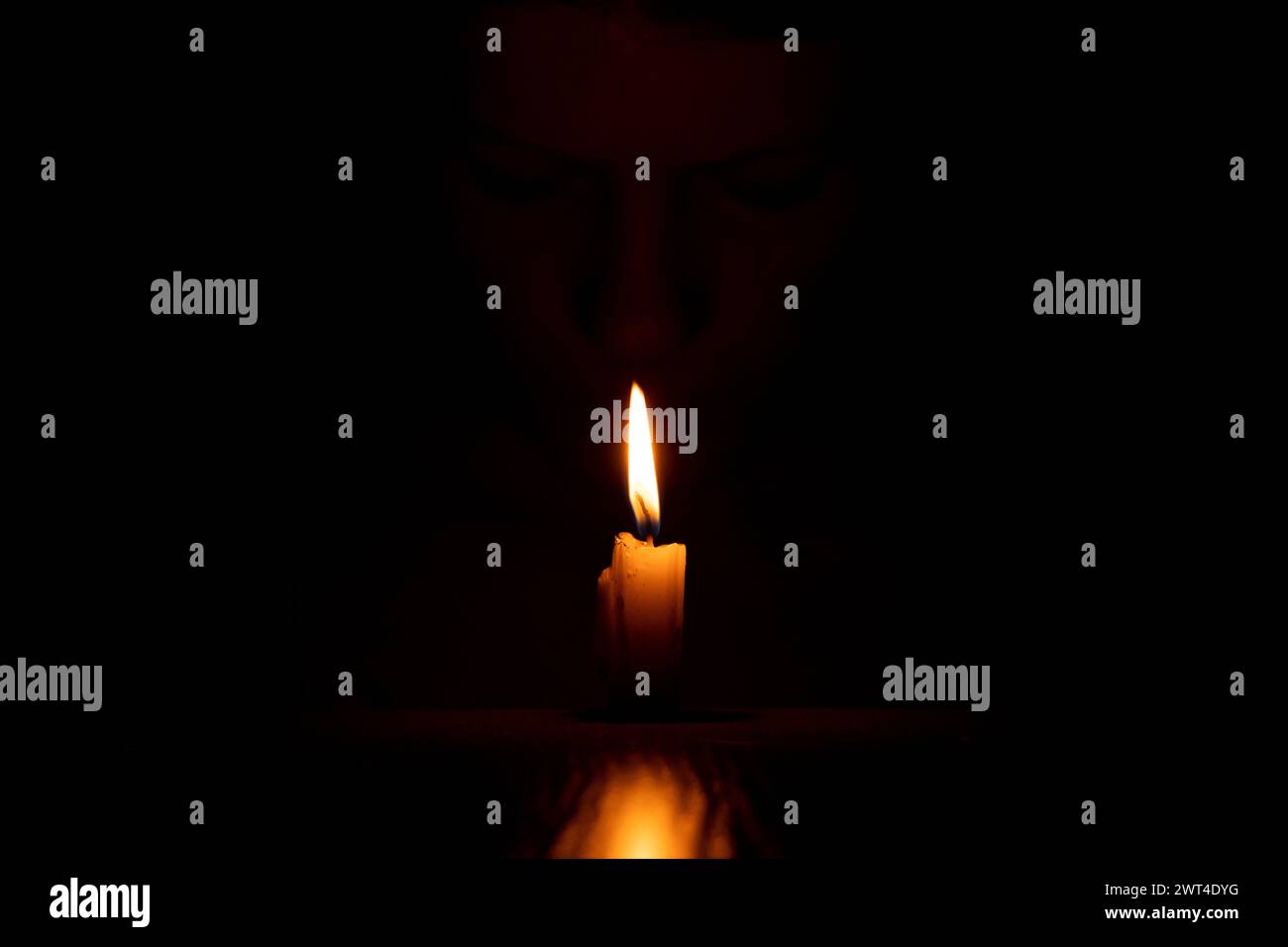 Il volto di una ragazza Ucraina al buio con una candela, una fiamma di candela e una ragazza Foto Stock