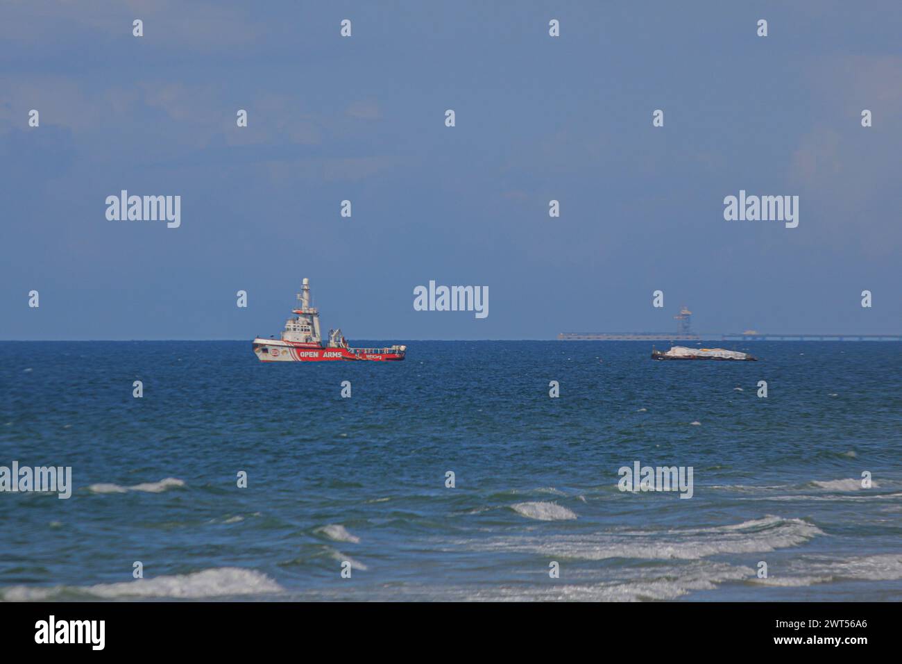 Gaza. 15 marzo 2024. Una nave, presidiata dall'organizzazione umanitaria spagnola Open Arms, è vista al largo della costa centrale della Striscia di Gaza, il 15 marzo 2024. La nave di primo soccorso, che attraversa il corridoio marittimo umanitario Cipro-Gaza, ha raggiunto la costa dell'enclave palestinese venerdì e ha iniziato a scaricare il suo carico, hanno detto fonti palestinesi. Crediti: Rizek Abdeljawad/Xinhua/Alamy Live News Foto Stock