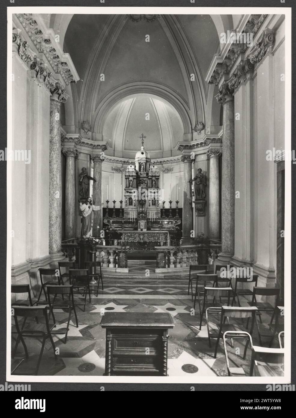 Umbria Perugia Spello S. Lorenzo. Hutzel, Max 1960-1990 S. Lorenzo (1120) sorge sul sito dell'ex S. Ercolano. Vista esterna del portale (XIII secolo) e della facciata (rimodellata nel 1540). Le vedute interne si concentrano sulla pittura e la scultura (XV-XVIII secolo): Intarsia di marmo fonte battesimale (1607); baldacchino dell'altare maggiore (un'imitazione di quella di San Pietro, Roma); coro in legno di intarsia; armadio e petto in legno nella Sacrestia con la figura intarsiata di Mosè, Noè e Zaccaria; pulpito in legno con bassorilievi del Martirio di S. Lorenzo; affreschi nella ca neoclassica Foto Stock