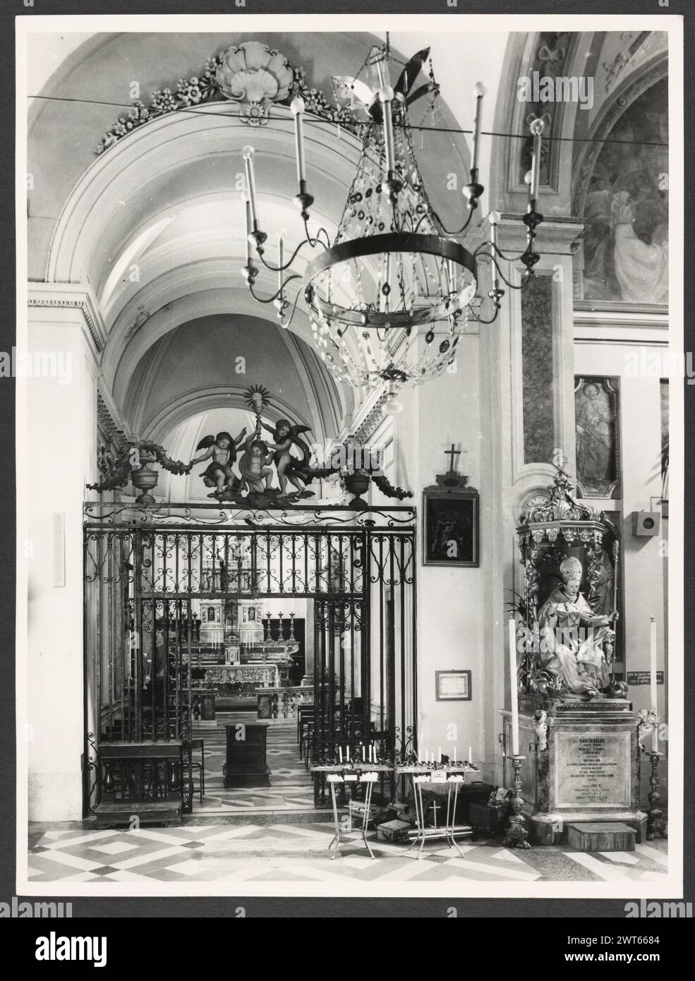 Umbria Perugia Spello S. Lorenzo. Hutzel, Max 1960-1990 S. Lorenzo (1120) sorge sul sito dell'ex S. Ercolano. Vista esterna del portale (XIII secolo) e della facciata (rimodellata nel 1540). Le vedute interne si concentrano sulla pittura e la scultura (XV-XVIII secolo): Intarsia di marmo fonte battesimale (1607); baldacchino dell'altare maggiore (un'imitazione di quella di San Pietro, Roma); coro in legno di intarsia; armadio e petto in legno nella Sacrestia con la figura intarsiata di Mosè, Noè e Zaccaria; pulpito in legno con bassorilievi del Martirio di S. Lorenzo; affreschi nella ca neoclassica Foto Stock