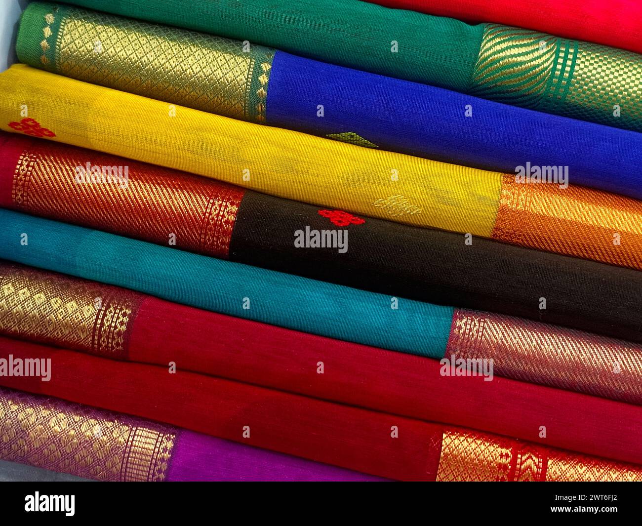 Vista ravvicinata di saris o sari impilati in esposizione nel negozio al dettaglio, da utilizzare come sfondo tessile indiano. Foto Stock