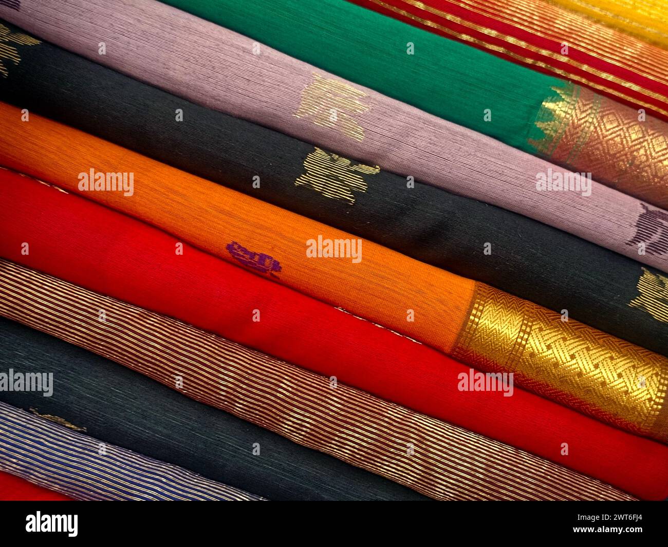 Vista ravvicinata di saris o sari impilati in esposizione nel negozio al dettaglio, da utilizzare come sfondo tessile indiano. Foto Stock