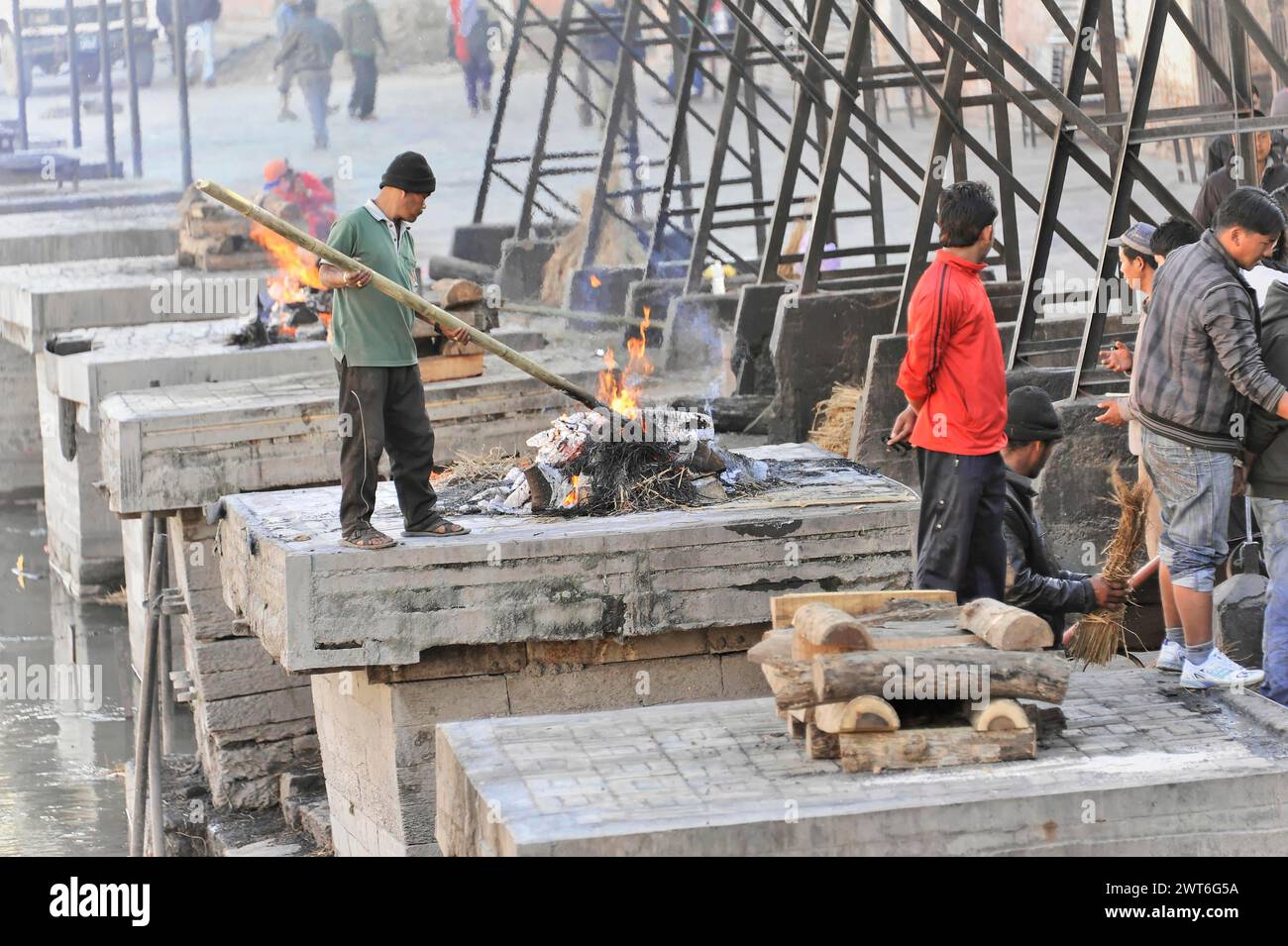 Rituale che brucia con gente in piedi intorno a un incendio su piattaforme di cemento, la valle di Kathmandu. Kathmandu, Nepal Foto Stock