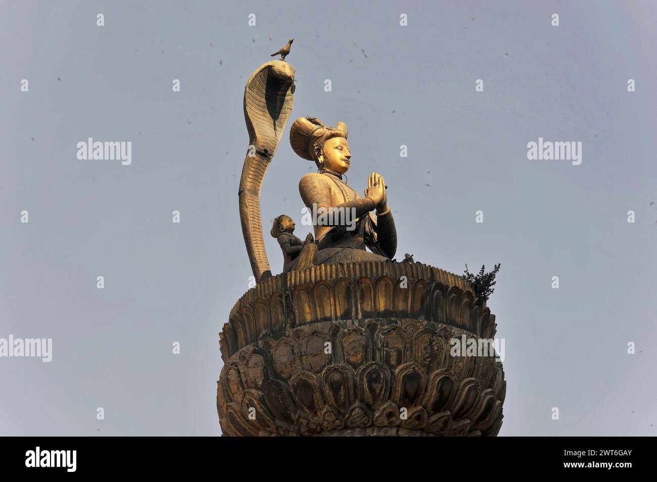 Statua con le mani piegate e un serpente di fronte a un cielo limpido, la valle di Kathmandu. Kathmandu, Nepal Foto Stock