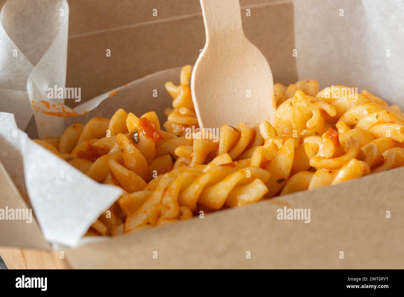 Fusilli in salsa di pomodoro ed erbe aromatiche da asporto in un contenitore di cartone. Contenitore da asporto ecologico e privo di plastica biodegradabile Foto Stock