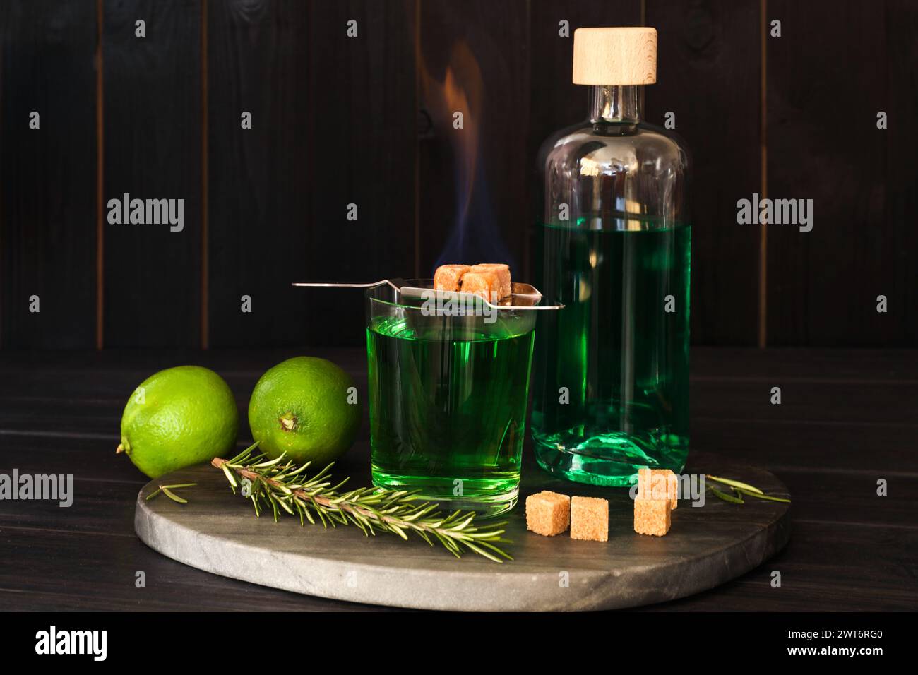 Absinthe in vetro, zucchero di canna fumante, rosmarino e calce su un tavolo di legno. Bevanda alcolica Foto Stock