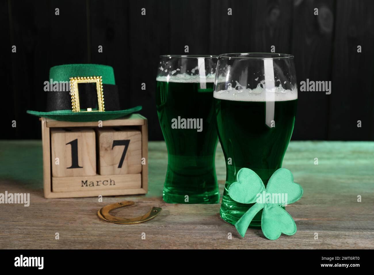 St Il giorno di Patrick festeggia il 17 marzo. Birra verde, calendario a blocchi, cappello di leprechaun, ferro di cavallo e foglia di trifoglio decorativa su un tavolo di legno Foto Stock