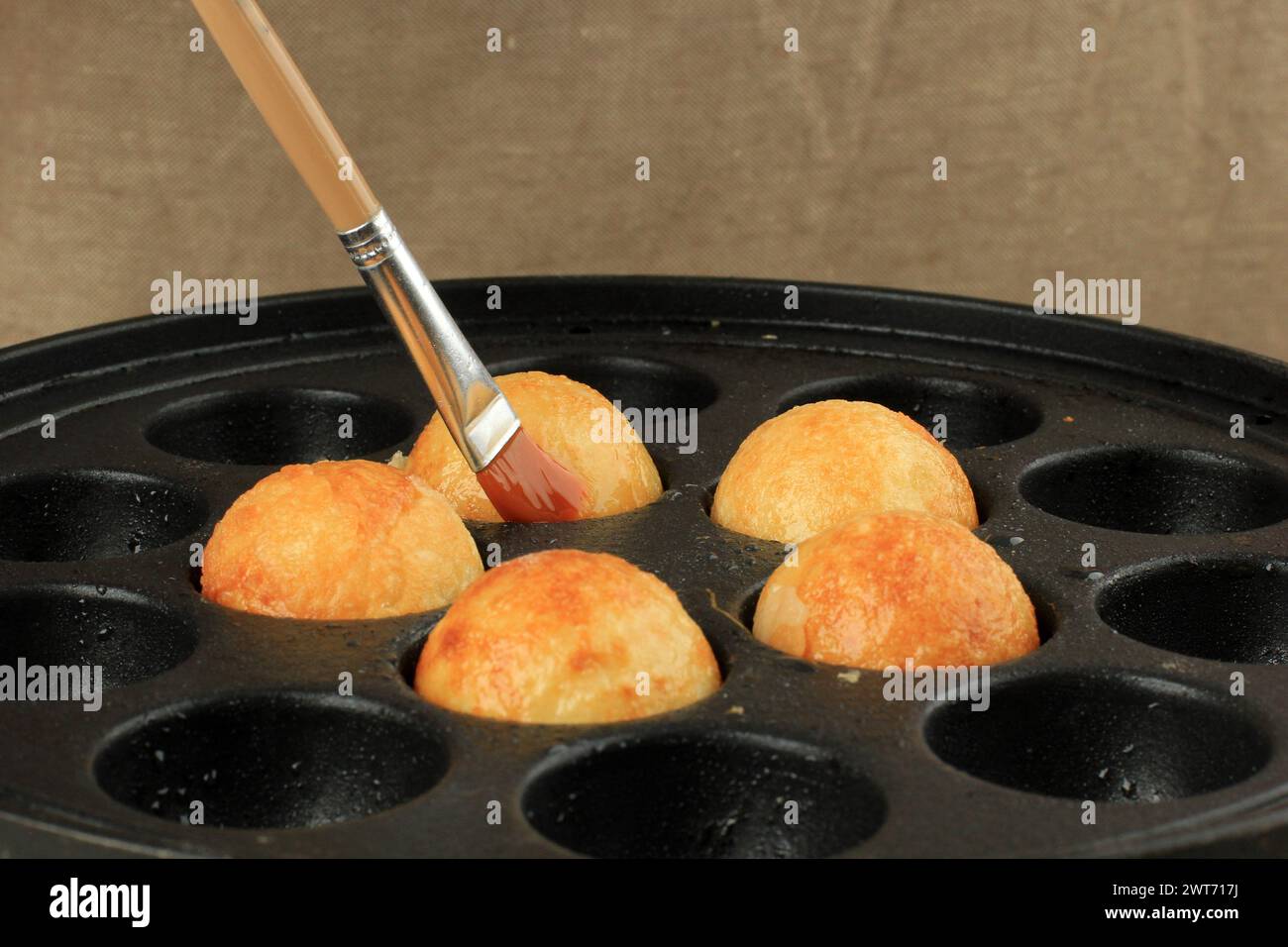 Spazzolare la pentola Takoyaki con olio, preparare le palline Takoyaki Foto Stock