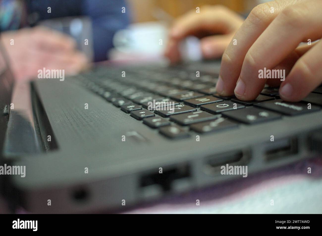 adolescente premendo i tasti di un portatile mentre i suoi genitori bevono una tazza di caffè Foto Stock