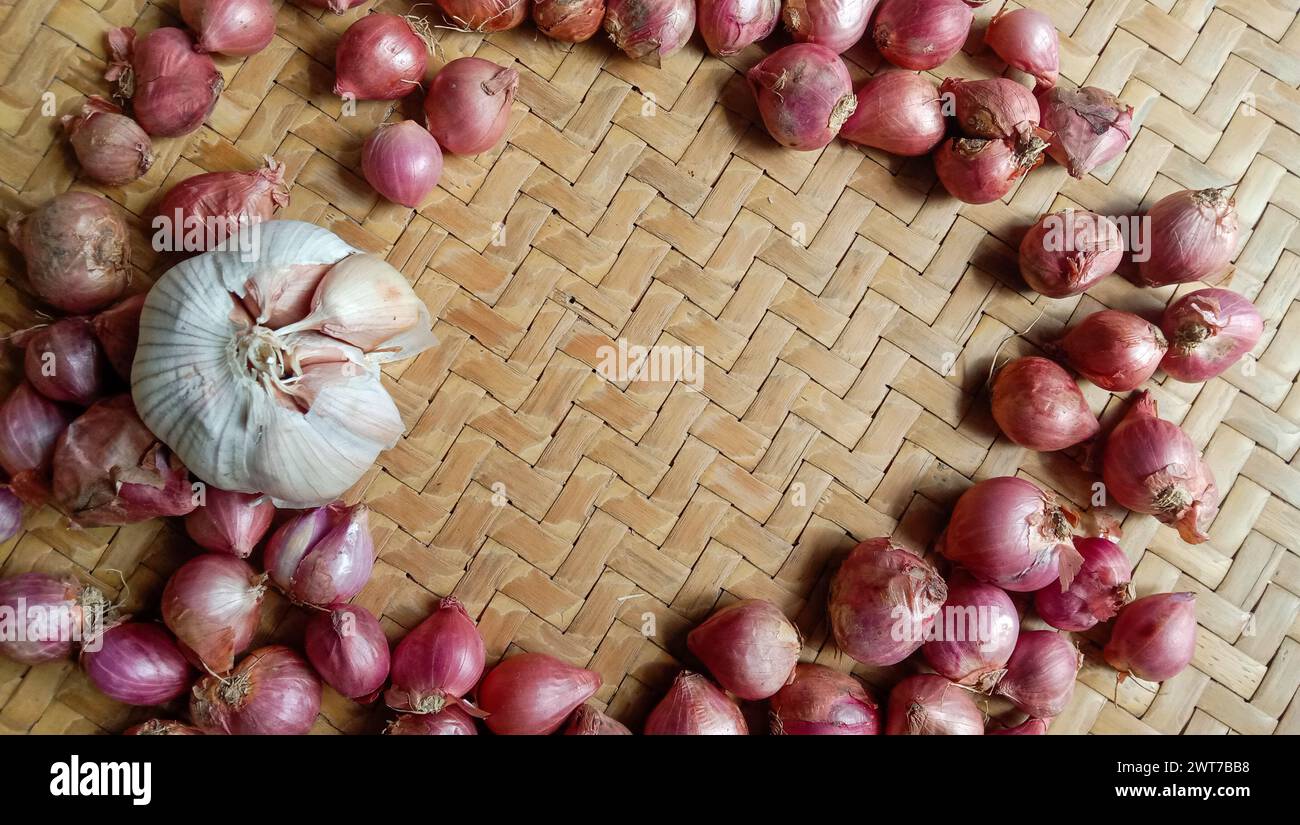 Foto di spezie sotto forma di scalogni, aglio, peperoncini e uova disposte in un bambù intrecciato Foto Stock