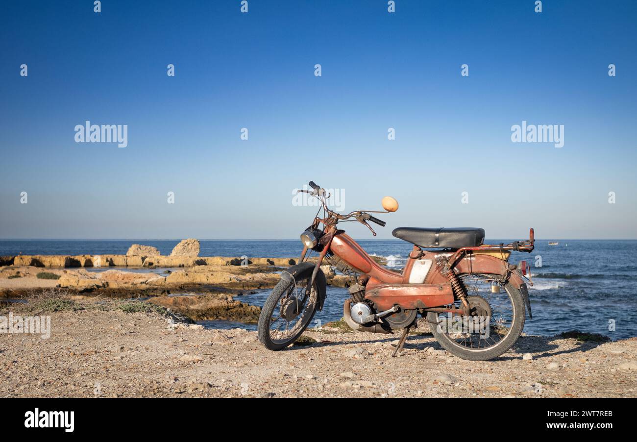 Un vecchio scooter parcheggiato vicino al mare a Borg Errass a Capo Africa, Mahdia, Tunisia Foto Stock