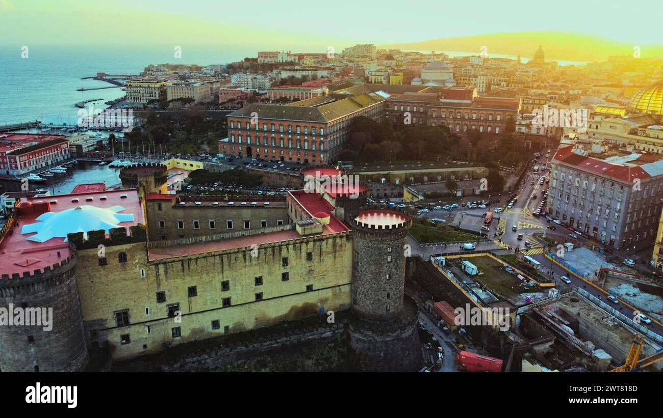 Vista droni della città di Napoli, con un grande castello e una splendida luce del tramonto. Foto Stock