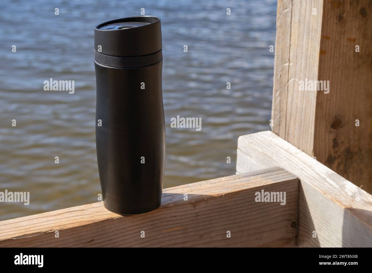 Termos neri su tavola di legno con fondo in acqua blu Foto Stock