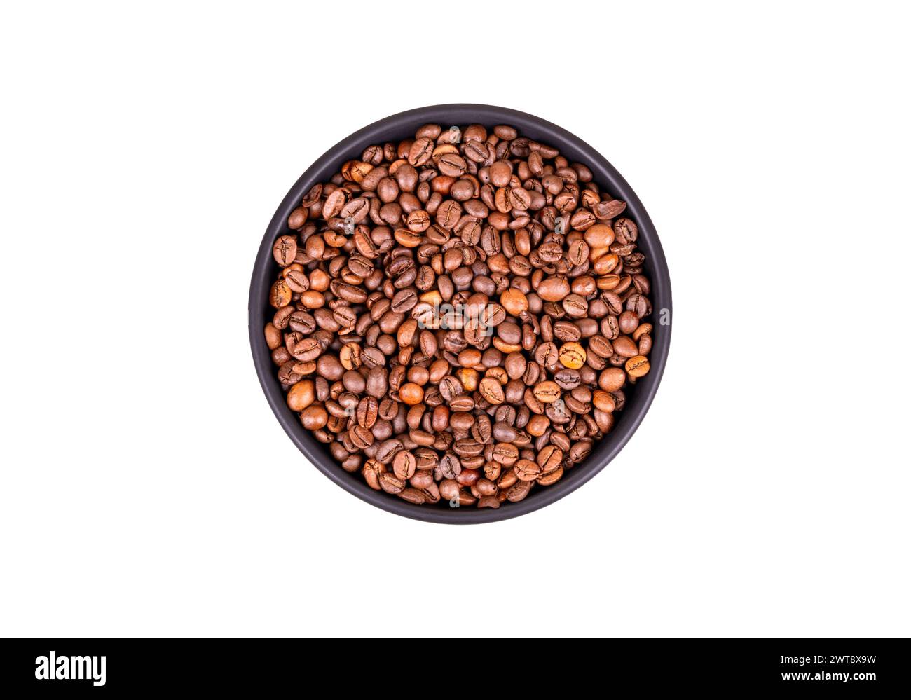 Tostatura dei chicchi di caffè in una ciotola in ceramica nera isolata su sfondo bianco, vista dall'alto. Foto Stock