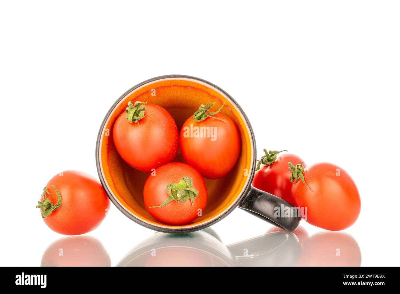 Diversi pomodori da cocktail maturi con tazza in ceramica, macro, isolati su sfondo bianco. Foto Stock