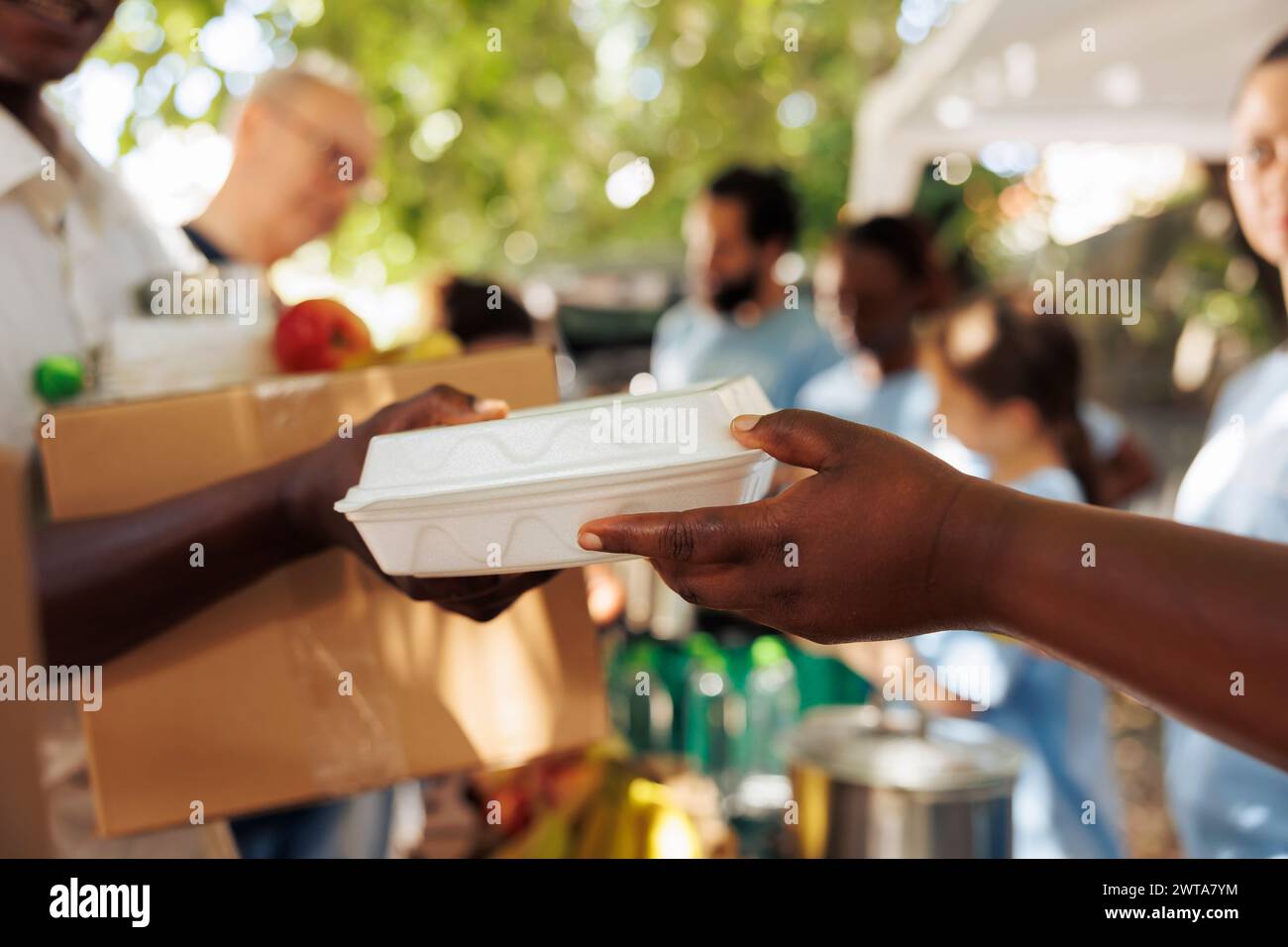 Volontario di origine afroamericana offre pasti caldi a un individuo povero e affamato. Foto incentrate sulla persona meno fortunata che riceve cibo gratuito da un lavoratore caritatevole. Foto Stock