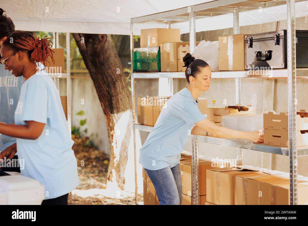 Organizzazione caritatevole che fornisce ai rifugiati oggetti essenziali non deperibili, offrendo una mano d'aiuto ai poveri e agli affamati. La volontaria caucasica organizza scatole di donazione per la distribuzione. Foto Stock