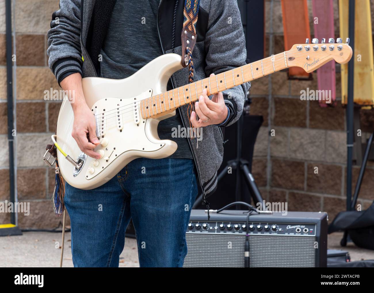 Primo piano di uomini dalle spalle alle ginocchia che suonano una chitarra elettrica bianca sul palco della Winter Texas Fiesta 2024, Mission, Texas, USA. Foto Stock