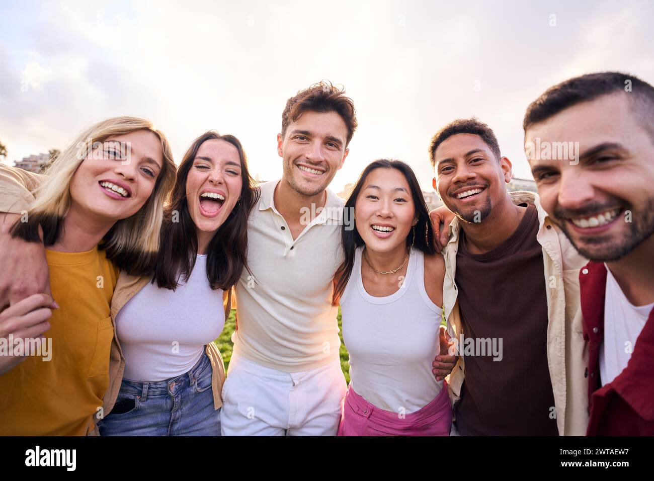 Un gruppo di amici multirazziali che si divertono all'aperto nel parco. Guardando la fotocamera e sorridendo. Foto Stock