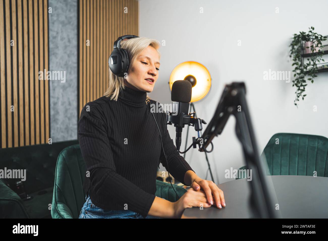Donna caucasica bionda dai capelli corti che lavora su un podcast dal vivo, tiro medio. Foto di alta qualità Foto Stock