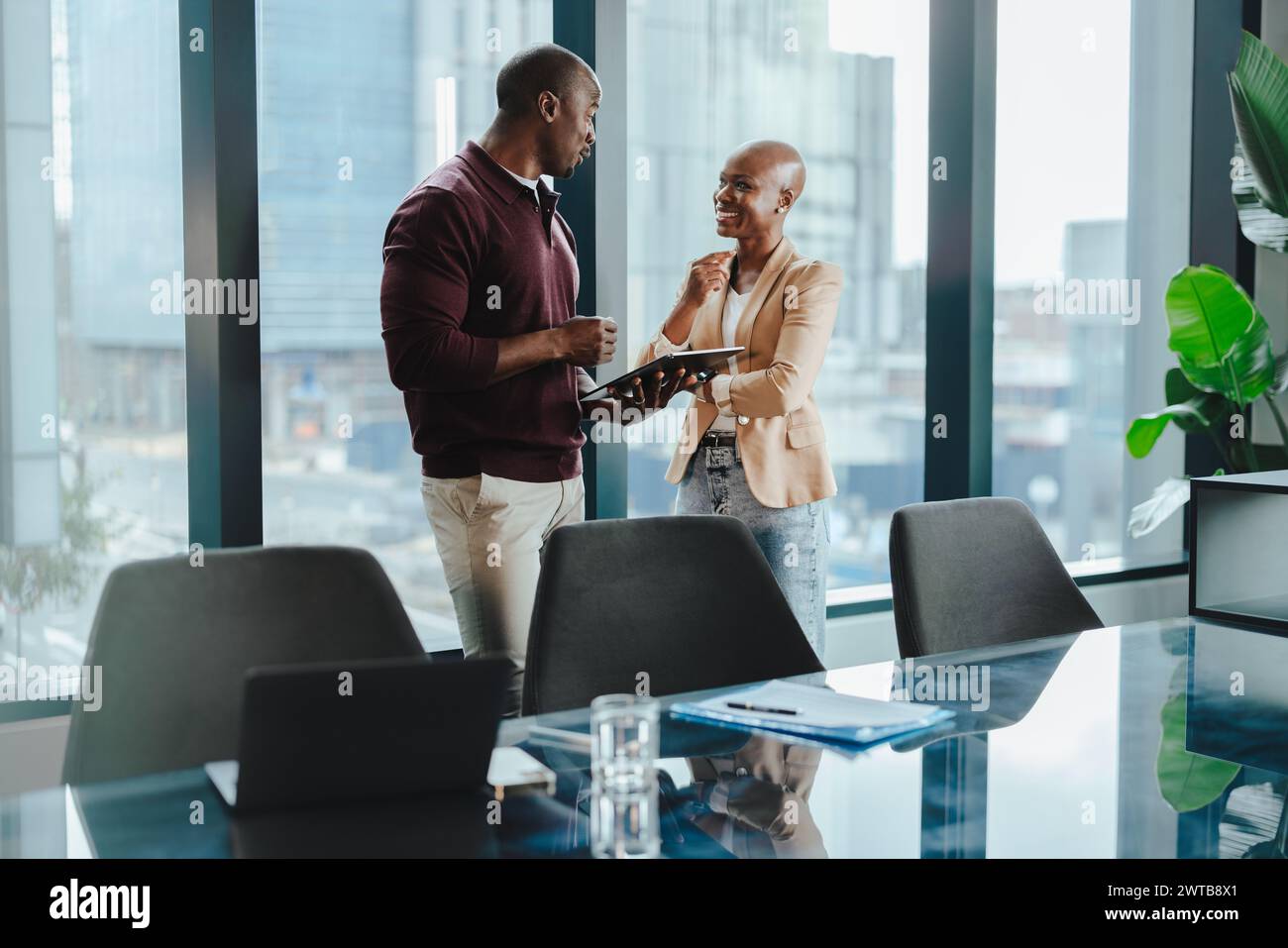 Due professionisti collaborano e discutono idee in un ufficio moderno. Utilizzano un tablet durante la loro riunione di lavoro di successo. I felici colleghi d Foto Stock