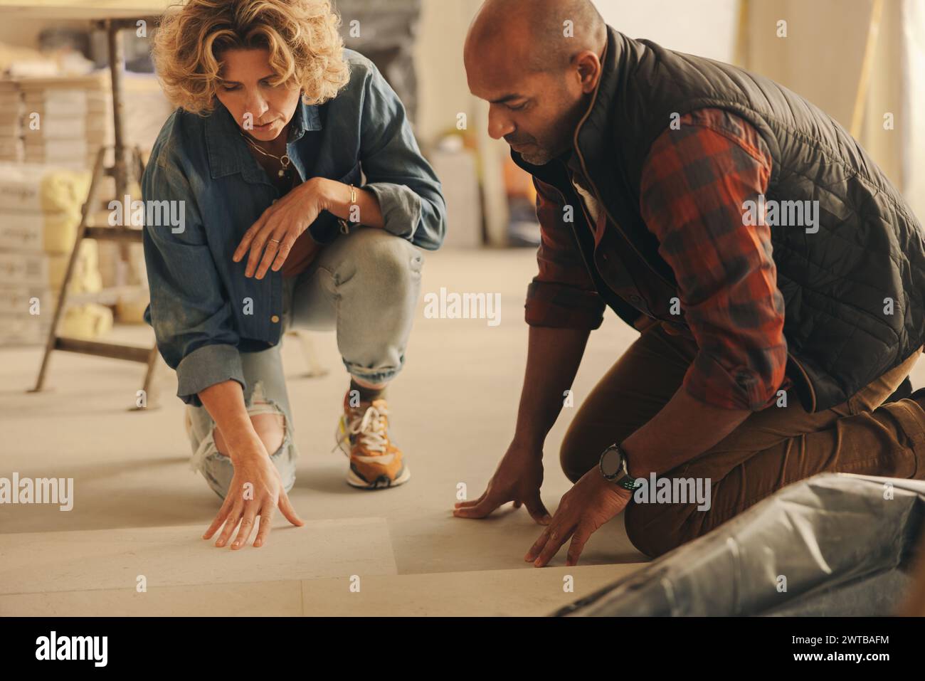 Proprietari di case che collaborano alla ristrutturazione di una casa. Discutono e pianificano la riprogettazione delle piastrelle del pavimento della loro cucina. Coppia sposata che lavora insieme, Foto Stock