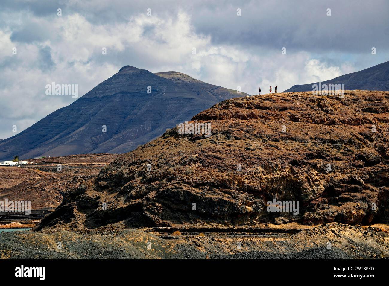 Tre persone su rocce laviche sulla costa di Janubio, Costa del Janubio, Lanzarote, Isole Canarie, Isole Canarie, Spagna Foto Stock