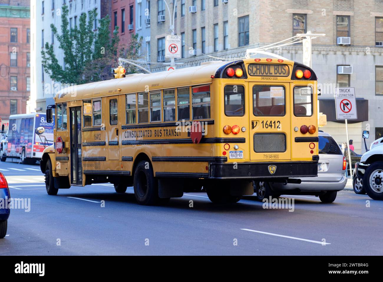 Vista laterale di uno scuolabus giallo in movimento su una strada della città, nel centro di Manhattan, Manhattan, New York City, Stati Uniti, nord America Foto Stock