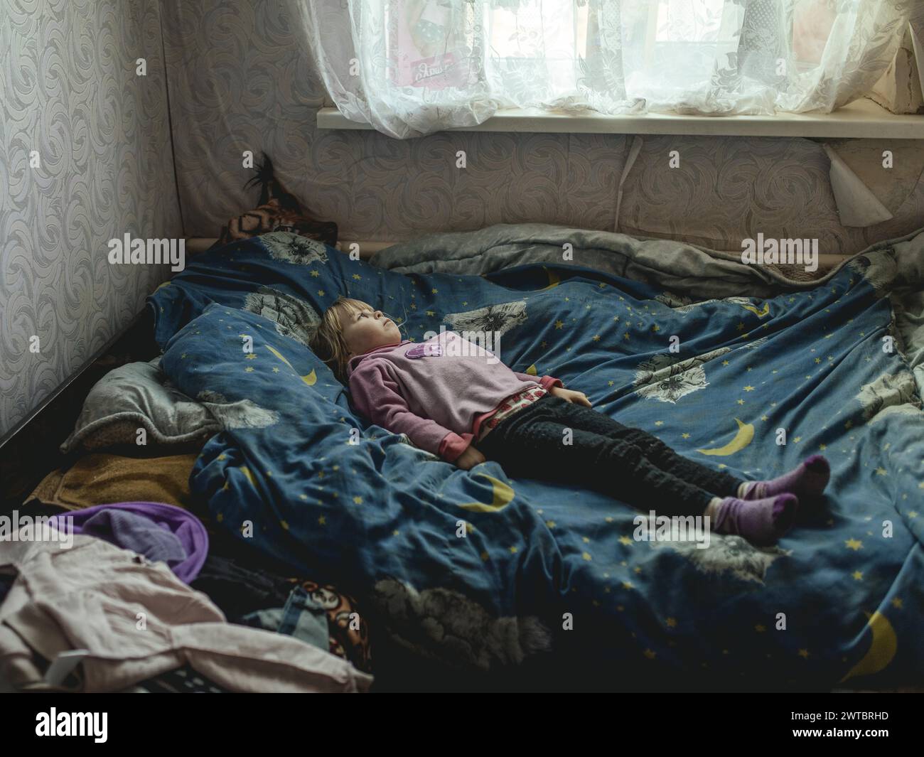 Angelina, 9 anni, sul suo letto. Il villaggio di Borshchivka era sotto l'occupazione russa. Ha disturbi d'ansia. Angelina e sua nonna Foto Stock