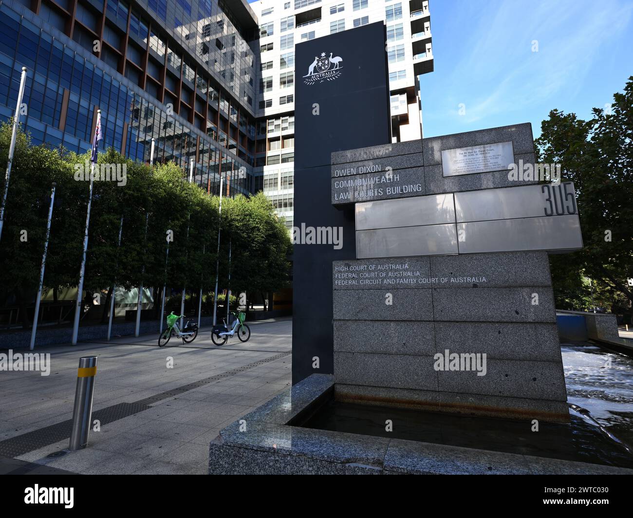 Cartello all'esterno dell'edificio Owen Dixon Commonwealth Law Courts, sede dell'alta Corte e della Corte Federale, con sullo sfondo biciclette a noleggio Lime Foto Stock