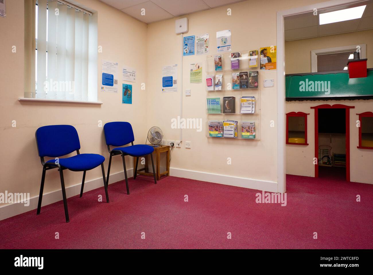 Una sala d'attesa dei medici con sedie, una casa wendy e un opuscolo Foto Stock