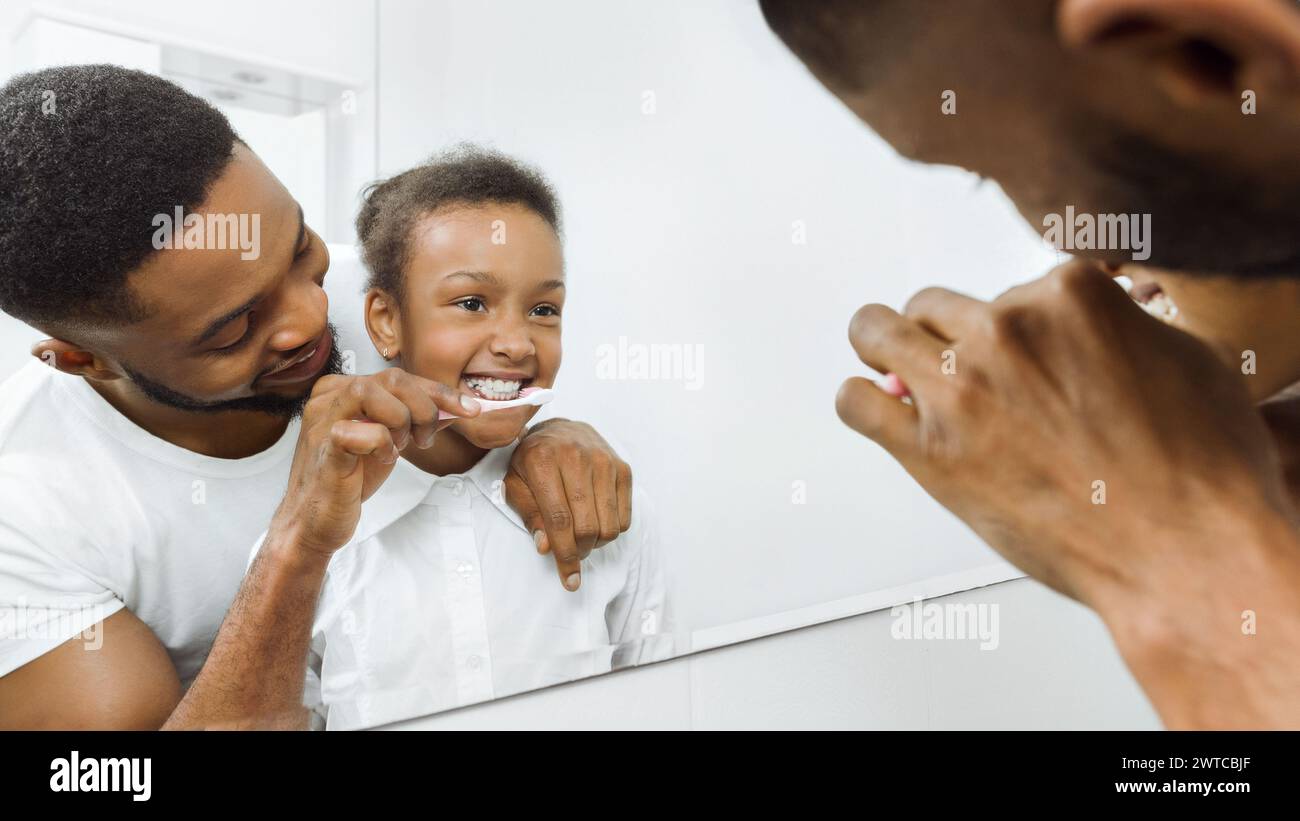 Padre premuroso che pulisce i denti della figlia in bagno Foto Stock