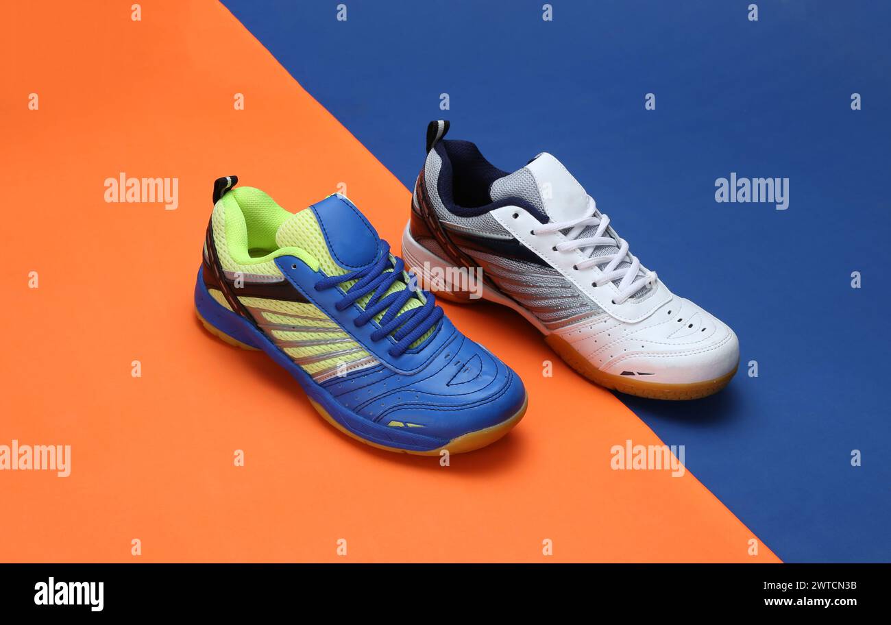 foto creativa delle scarpe da badminton su sfondo arancione blu Foto Stock