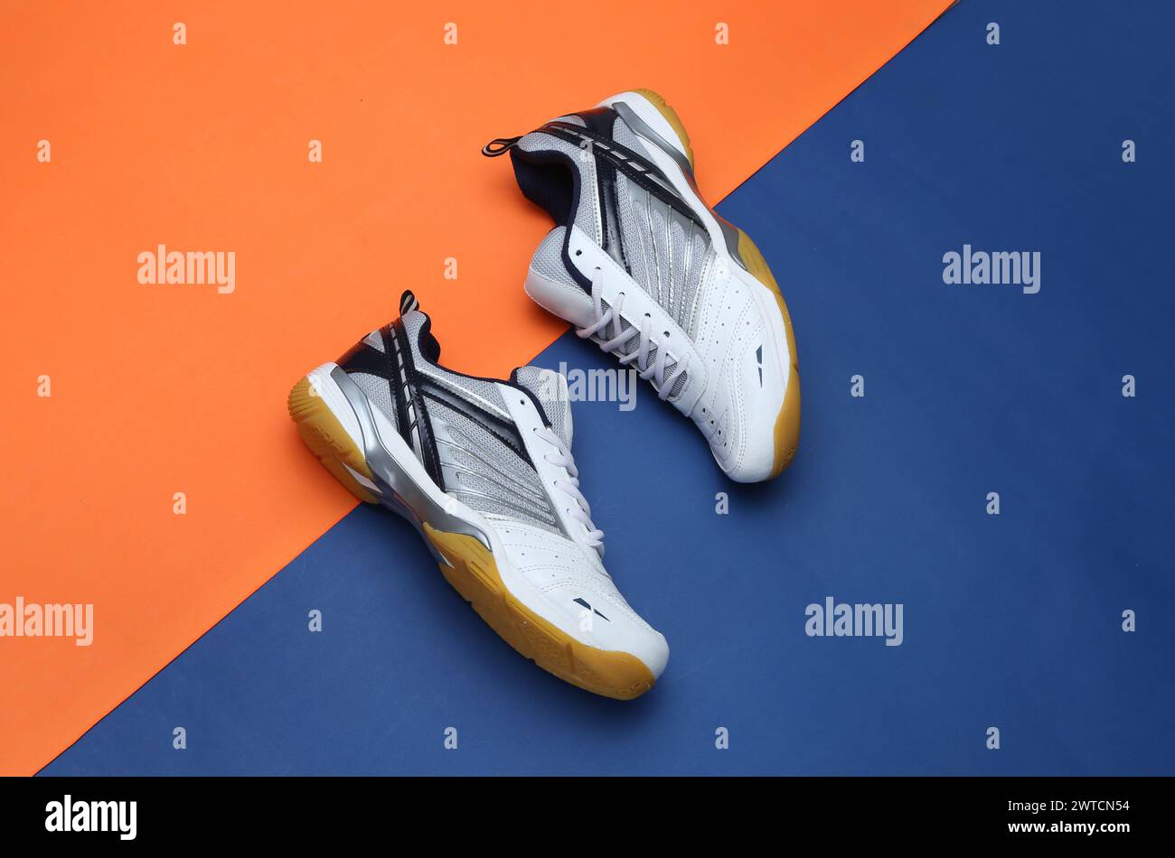 foto creativa delle scarpe da badminton su sfondo arancione blu Foto Stock