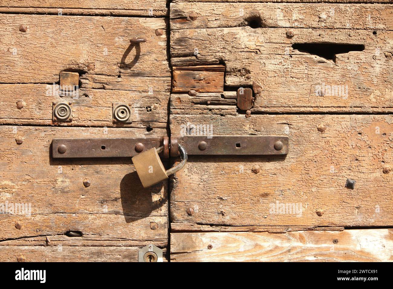 Cancello in legno rustico con serratura in metallo antico e senza maniglia, che evoca un senso di abbandono e una bellezza sbiadita Foto Stock