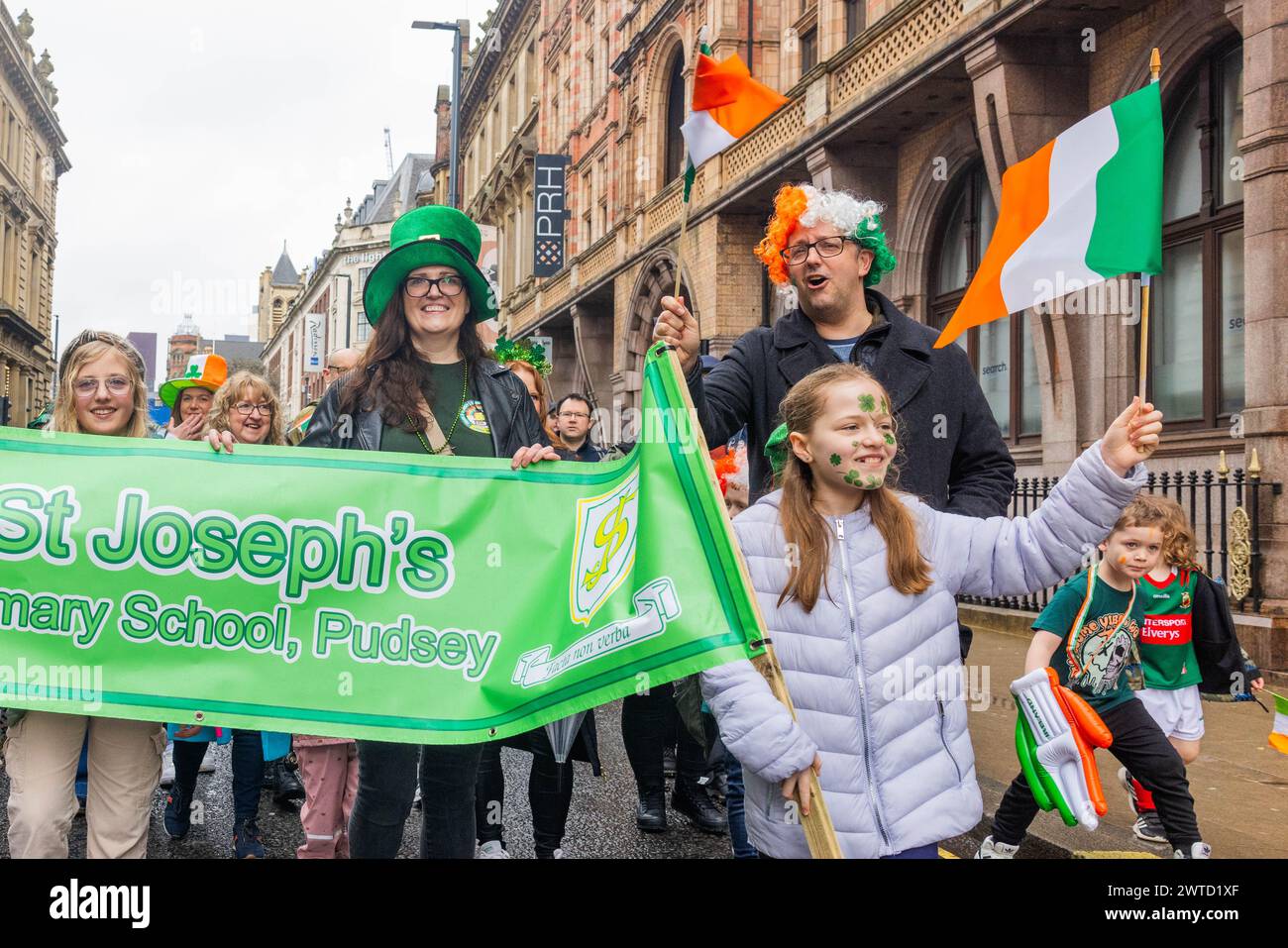 Leeds, Regno Unito. 17 MARZO 2023. I membri della scuola elementare di San Giuseppe (Pudsey) marciano lungo il percorso della parata sventolando le bandiere irlandesi alla parata del giorno di San Patrizio del 2024. Credito Milo Chandler/Alamy Live News Foto Stock