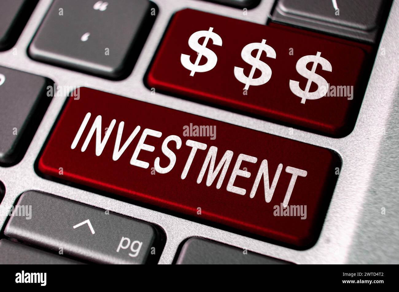 Testo dell'investimento e simbolo del dollaro sulle tastiere rosse dei notebook. Concetto di investimento aziendale. Foto Stock