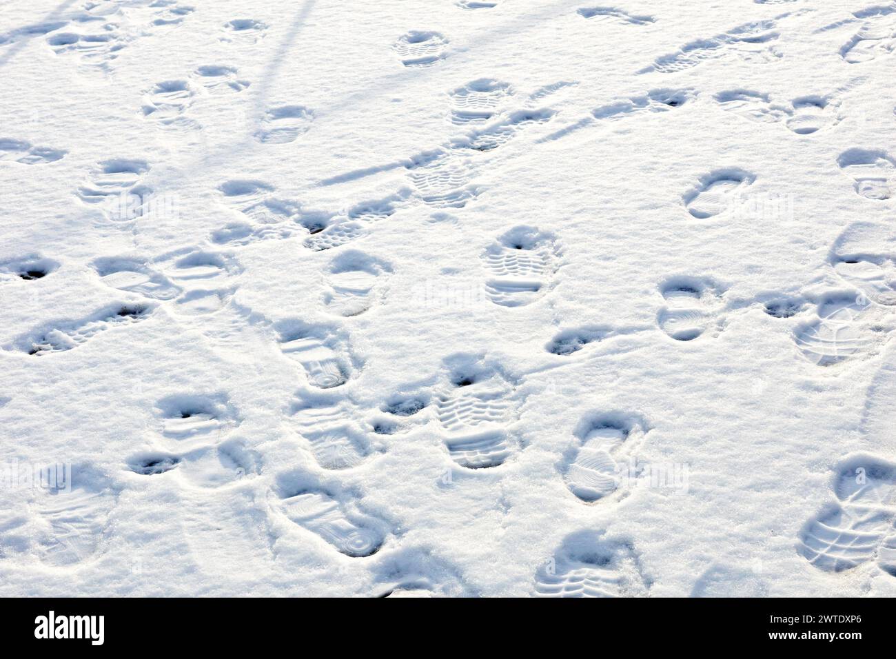 Impronte sulla neve, primo piano di diversi tracciati di bootprint e di scarpe che attraversano un marciapiede innevato durante l'inverno. Foto Stock