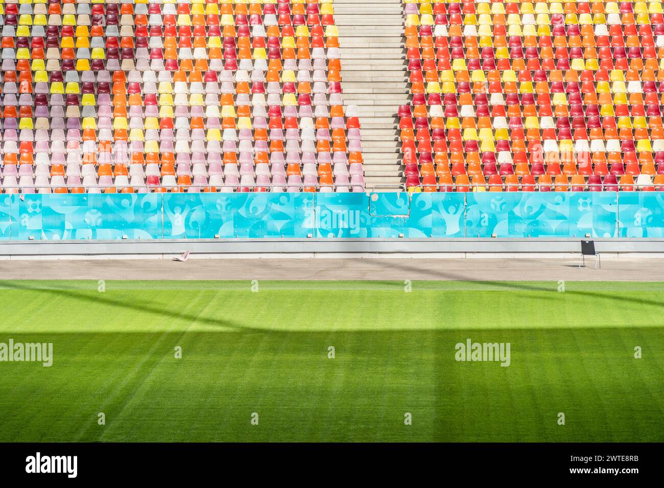 Stadio vuoto con sedie colorate in tribuna e prato verde Foto Stock