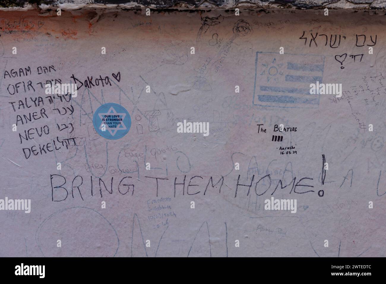 Abbey Road, Londra, Regno Unito. 17 marzo 2024. Un gruppo di studenti delle scuole superiori israeliane, sopravvissuti all’attentato terroristico del 7 ottobre 2023, che hanno visitato Londra nell'ambito di una delegazione organizzata da 7/10 Human Chain Project, scrivono messaggi sul muro dello studio Abbey Road per i loro 7 amici e vicini, ancora tenuti prigionieri a Gaza da quando sono stati portati via dalle loro case durante l'attacco palestinese in Israele 163 giorni fa. Il gruppo ha visitato gli studenti a Londra per condividere le loro storie e le terribili esperienze del massacro. Foto di Amanda Rose/Alamy Live News Foto Stock