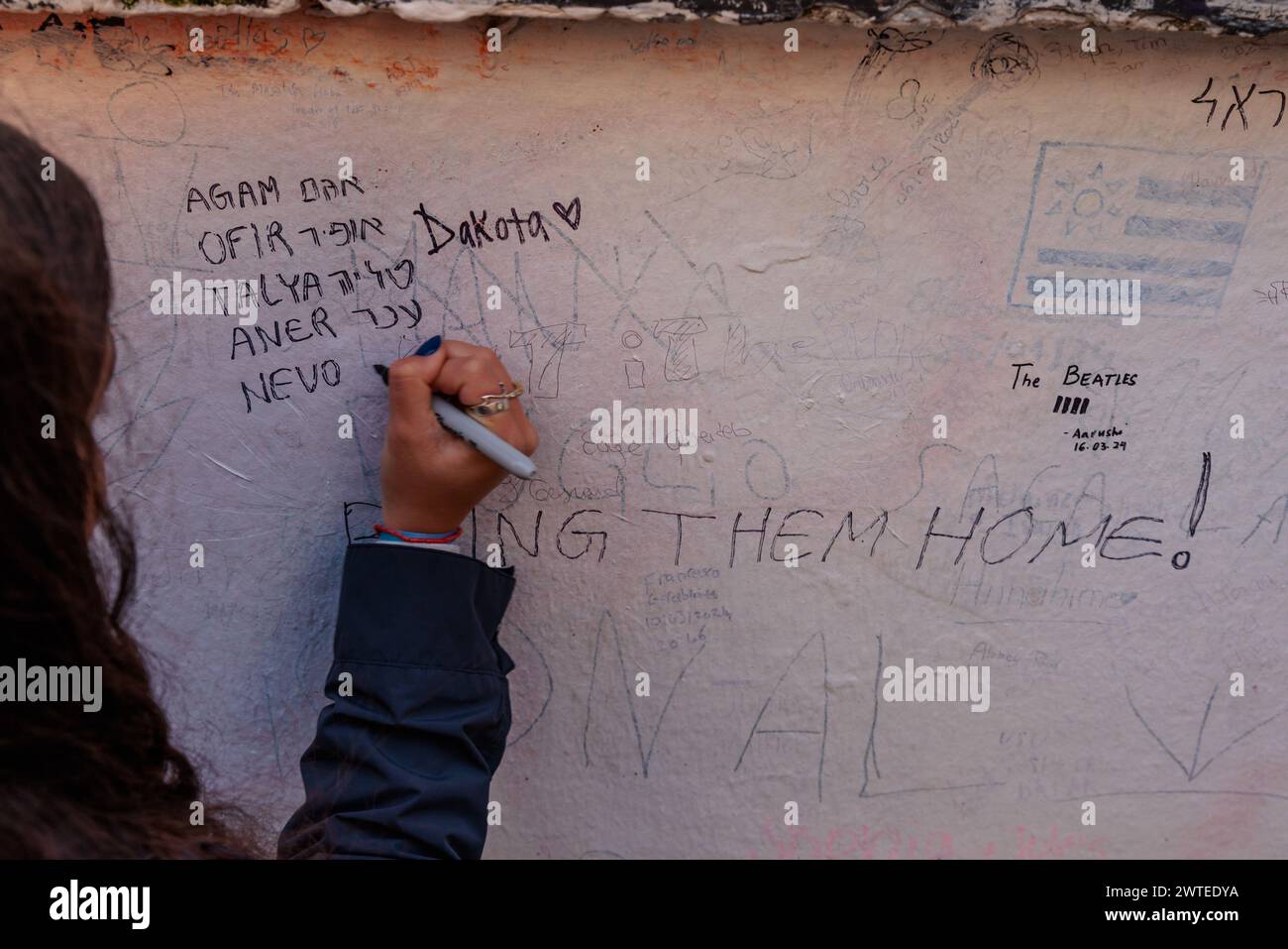 Abbey Road, Londra, Regno Unito. 17 marzo 2024. Un gruppo di studenti delle scuole superiori israeliane, sopravvissuti all’attentato terroristico del 7 ottobre 2023, che hanno visitato Londra nell'ambito di una delegazione organizzata da 7/10 Human Chain Project, scrivono messaggi sul muro dello studio Abbey Road per i loro 7 amici e vicini, ancora tenuti prigionieri a Gaza da quando sono stati portati via dalle loro case durante l'attacco palestinese in Israele 163 giorni fa. Il gruppo ha visitato gli studenti a Londra per condividere le loro storie e le terribili esperienze del massacro. Foto di Amanda Rose/Alamy Live News Foto Stock