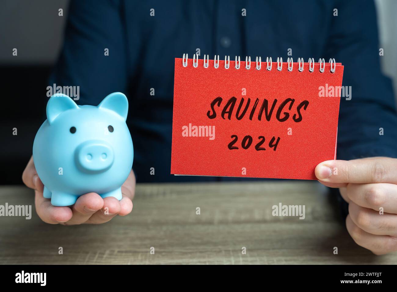 Concetto di risparmio 2024. Accumulare denaro per il nuovo anno. Pianificazione del budget e delle spese. Un blocco appunti nelle mani di un uomo d'affari e di un salvadanaio. Busin Foto Stock