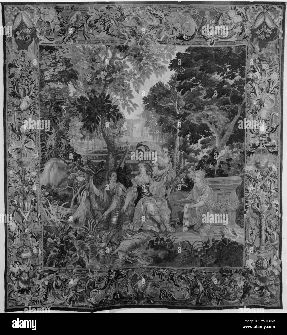 Diana e ninfe. Sconosciuto c. 1690-1710 arazzi materiali/tecniche: Sconosciuta Cultura: Flemish Weaving Center: Bruxelles storia della proprietà: French & Co. Iscrizioni: Marchio della città sulla guardia inferiore, destra del centro; monogramma tessuto nella guardia inferiore, destra [non leggibile nella fotografia] nella foresta, Diana, accompagnata da 3 ninfe, riposo dopo la caccia; ninfa tiene su coniglio morto (centro, primo piano); piedistallo in pietra con ghirlanda di fiori (R, primo piano); giardino stilizzato con fontane e scenografia architettonica (centro, sfondo) (BRD) rinceau e motivi di fogliame stilizzati terminano con fiori fioriti e interspizi Foto Stock
