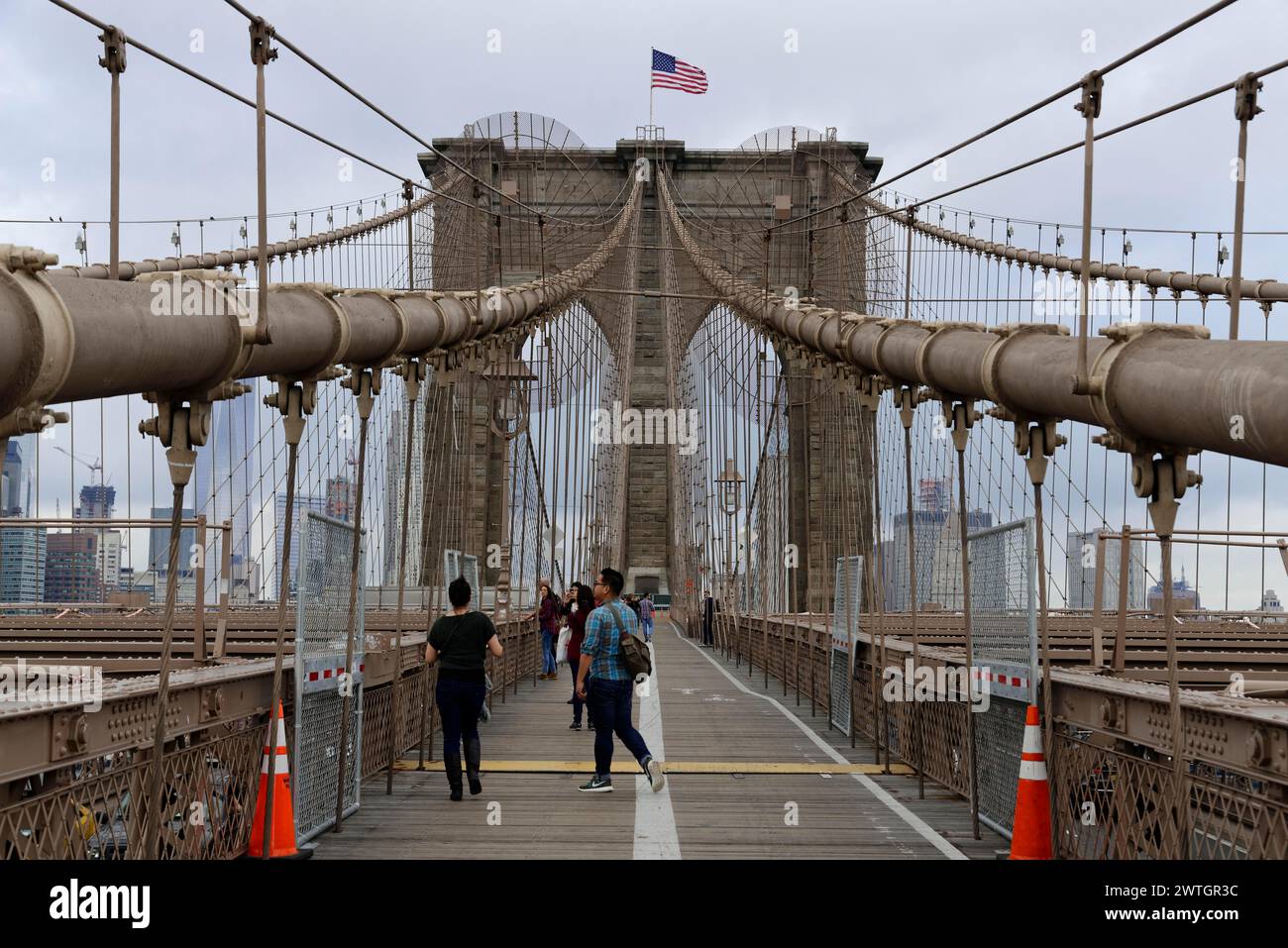 Le persone attraversano a piedi il Ponte di Brooklyn, che si presenta con la sua imponente struttura, Manhattan, New York, New York, Stati Uniti, nord America Foto Stock