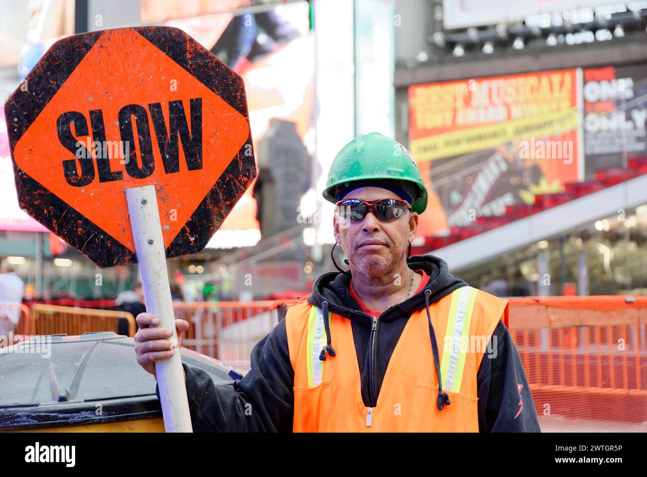 Un operaio edile è in possesso di un cartello di avvertimento "lento" e indossa un gilet e un casco di sicurezza, Manhattan, New York, New York, Stati Uniti, nord America Foto Stock