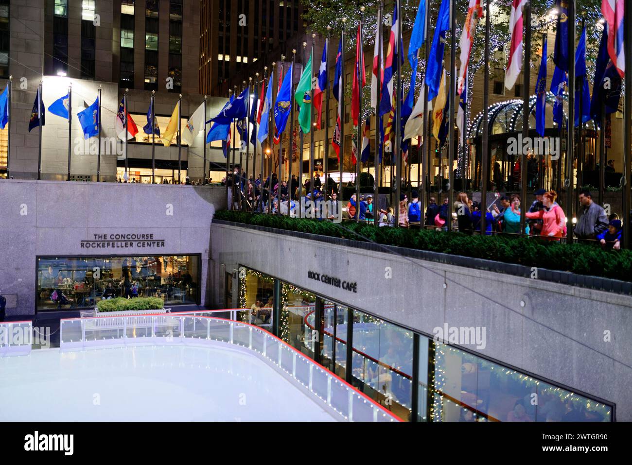 Persone che guardano la pista di pattinaggio su ghiaccio di Rockefeller Plaza, circondate da bandiere, Manhattan, New York City, New York, Stati Uniti, Nord America Foto Stock