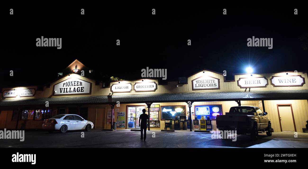 Un giovane che va al negozio di alimentari di un business center di notte a Mariposa, California Foto Stock